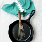 Clean cast iron skillet with a spatula and linen cloth