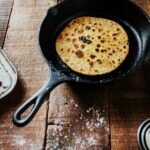 Flatbread cooking in a cast iron skillet on a wooden table