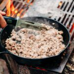 Cast iron skillet cooking over an open campfire
