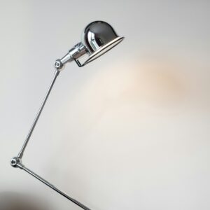 Chrome articulated desk lamp against a pale wall