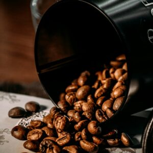 Whole roasted coffee beans spilling from a black canister