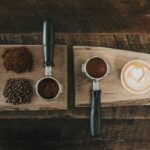 Ground coffee, beans and a finished latte laid out on wooden boards