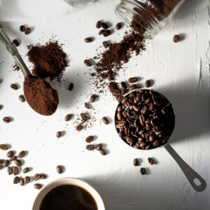 Ground coffee, beans and a filled cup on a white surface