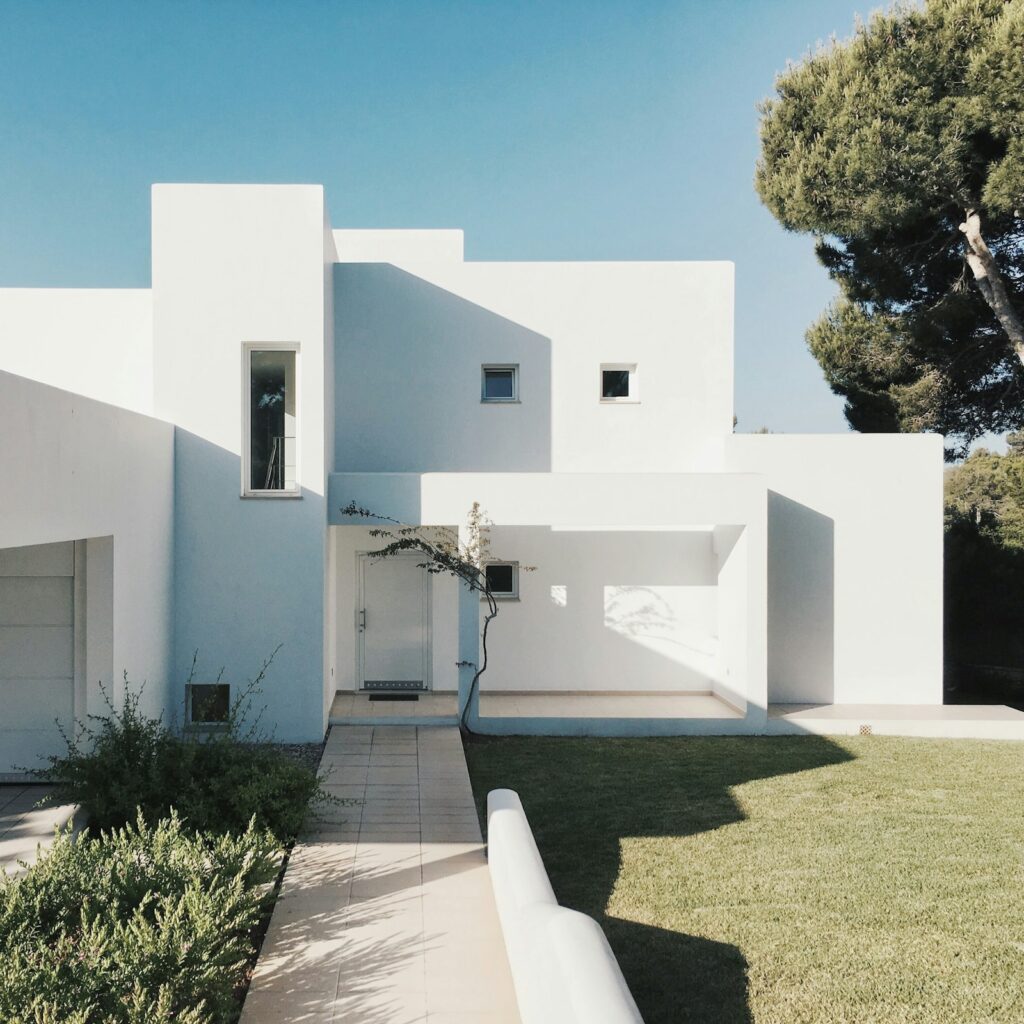Whitewashed minimalist villa facade with a landscaped lawn